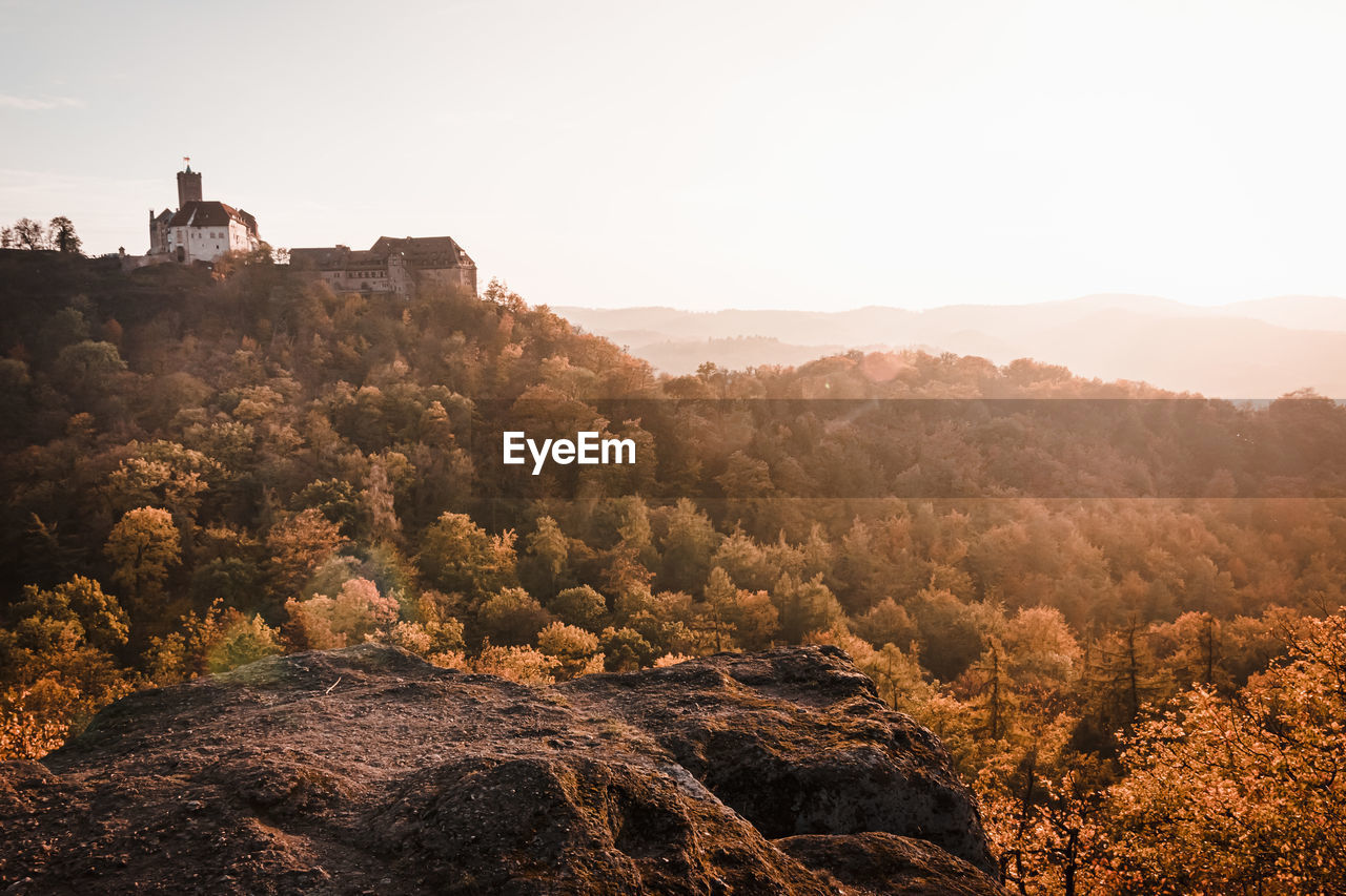 View of building on hill by forest against sky