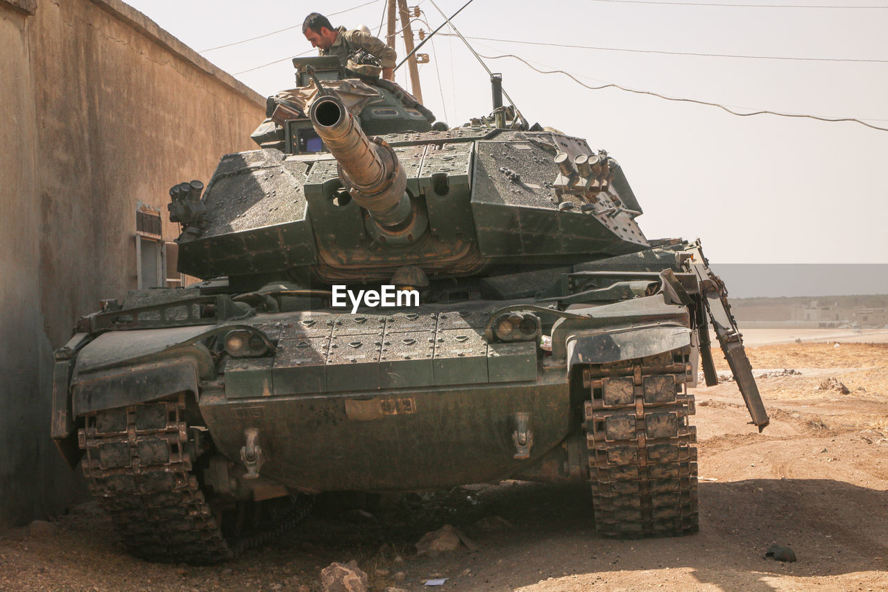 Man in armor tank on land against sky