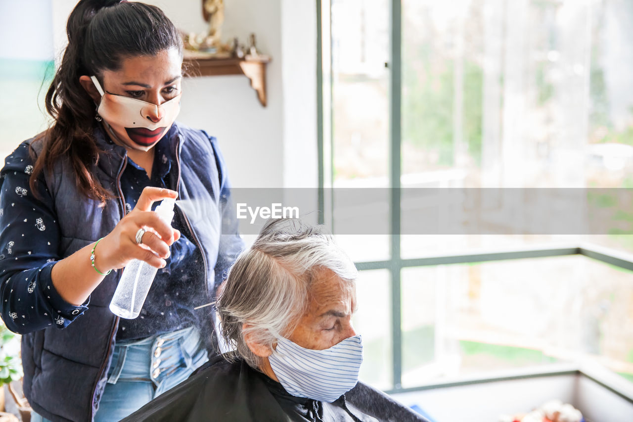 Beautician treating hair of customer at home