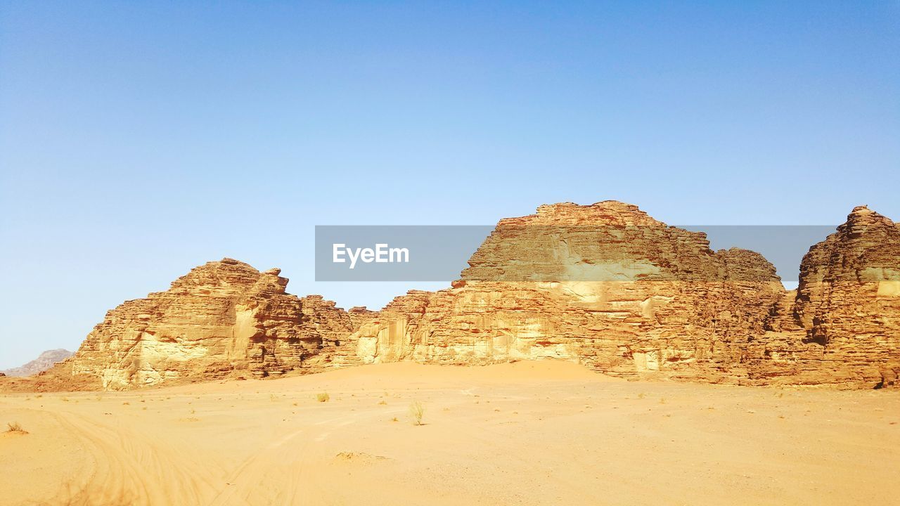 Rock formations on landscape against clear blue sky