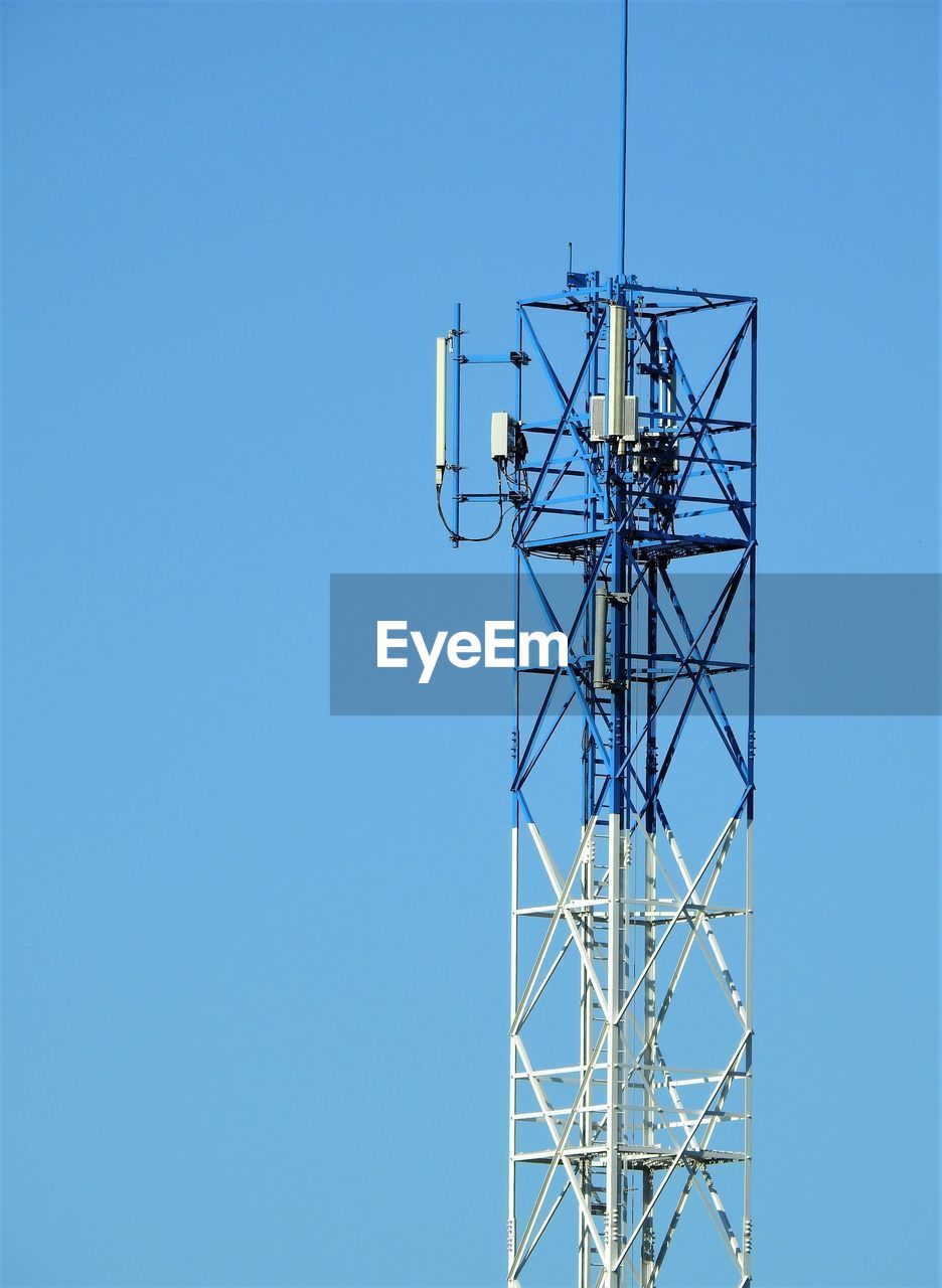 Low angle view of communications tower against clear blue sky