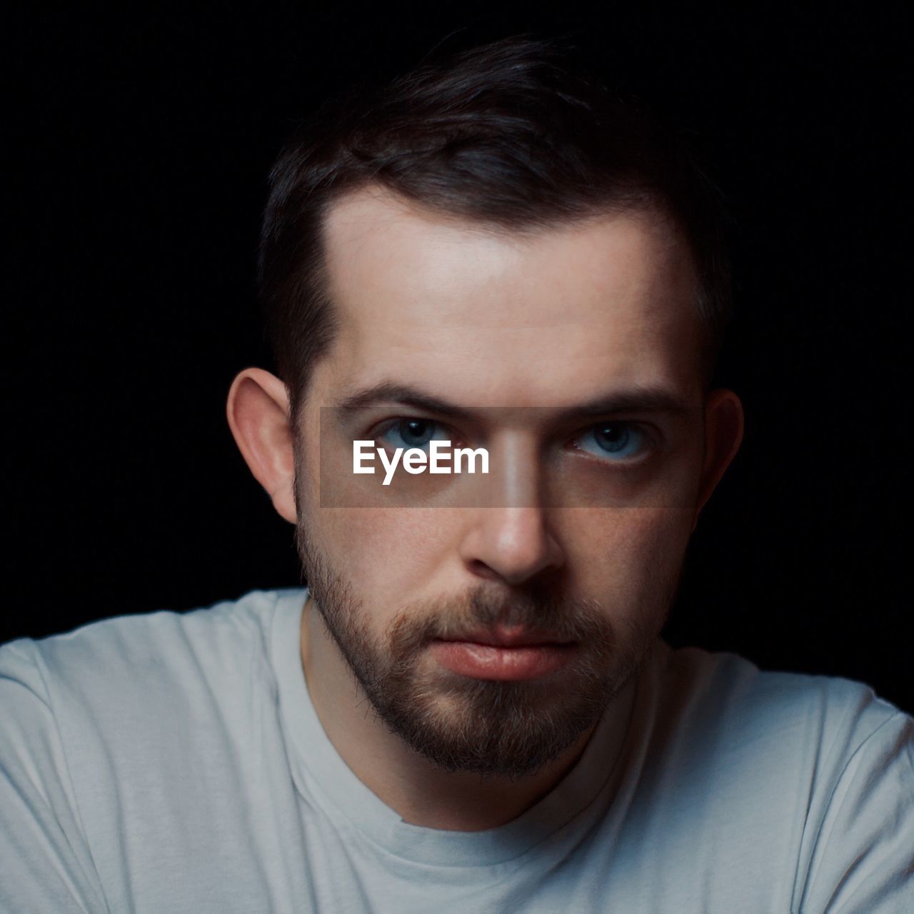 Portrait of young man against black background