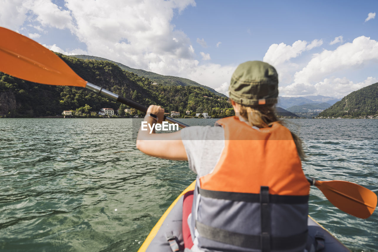 Woman wearing life jacket kayaking at lake