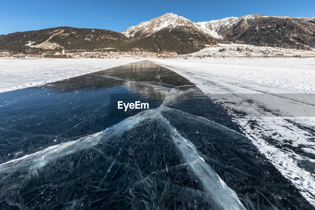  view of frozen lake and mountains against sky