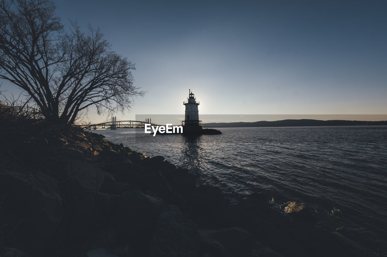 LIGHTHOUSE BY SEA AGAINST SKY AT SUNSET