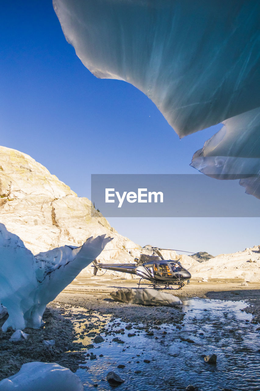 Helicopter landed just outside the entrance of a glacier cave.