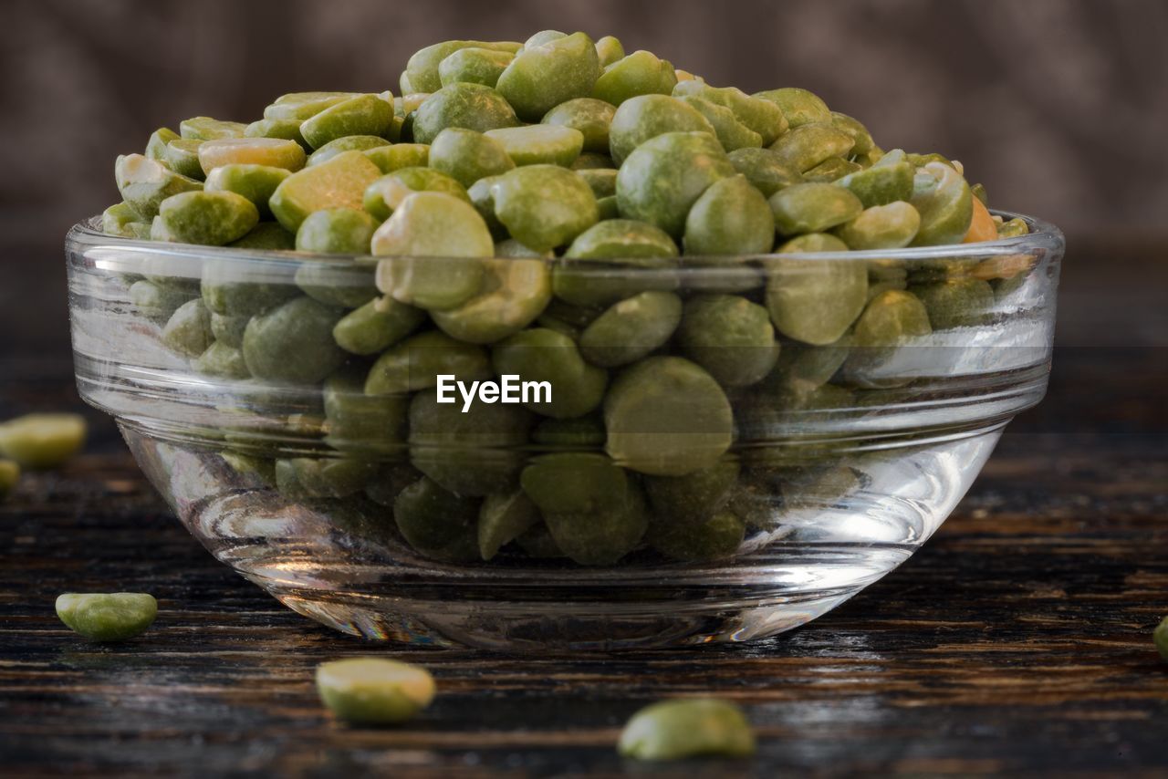 Close-up of green split peas in bowl on wooden table