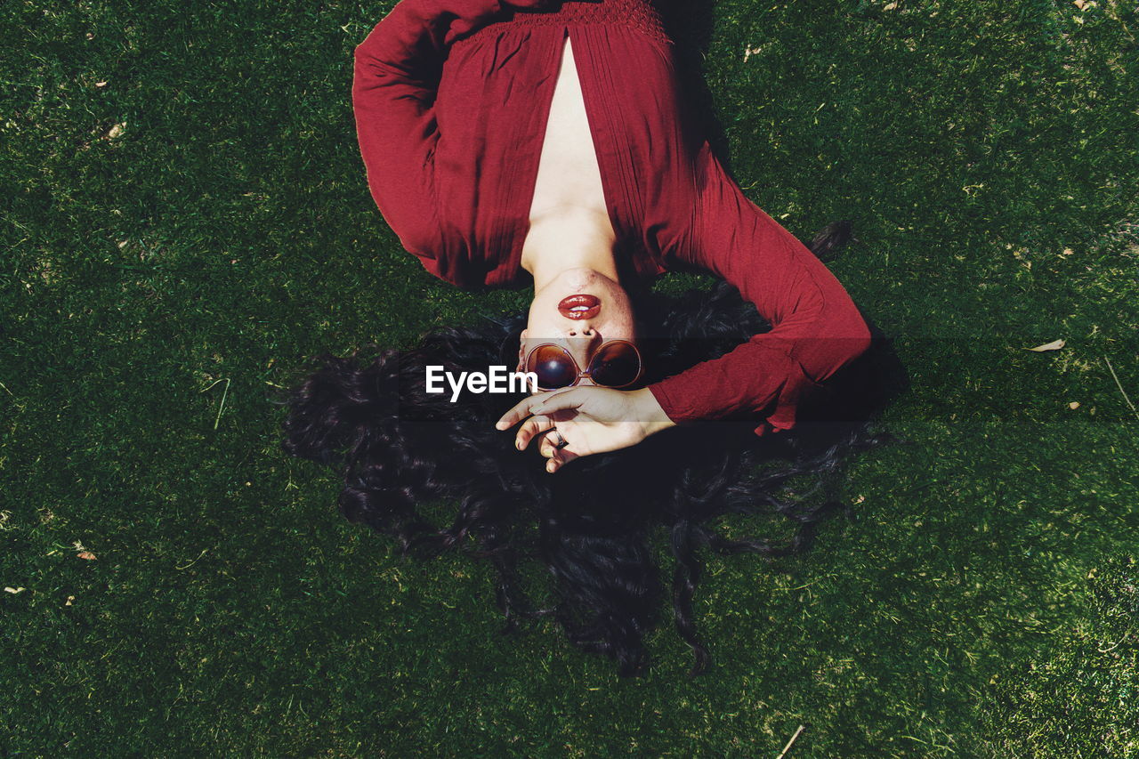 High angle view of young woman lying on grassy field