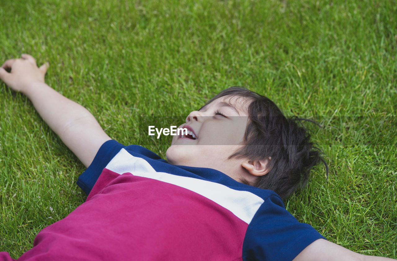 Low angle view of boy lying on grassy field