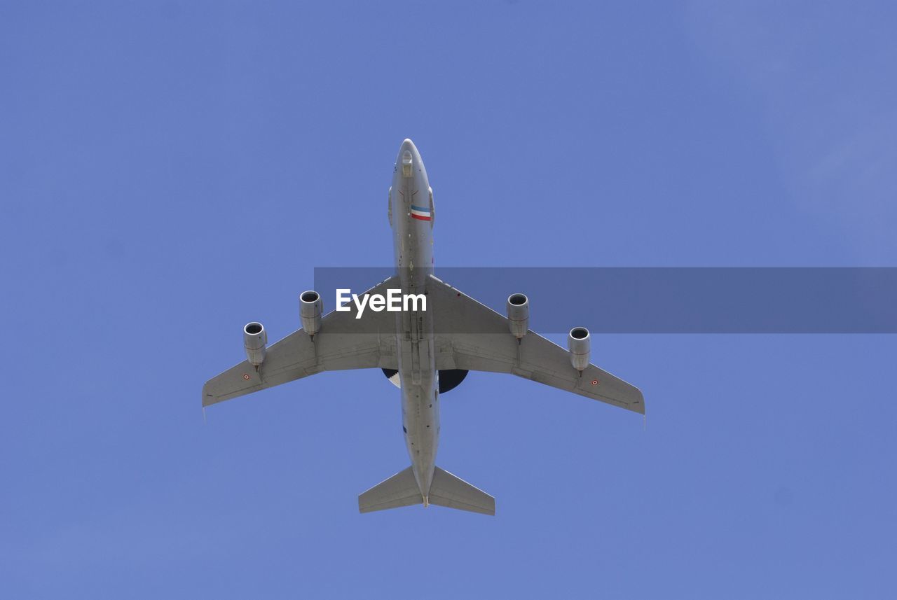 Low angle view of airplane flying against clear blue sky