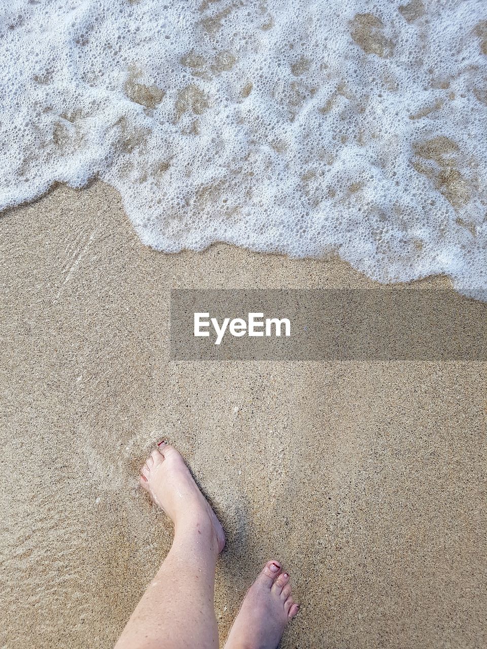 Low section of woman walking at sea shore