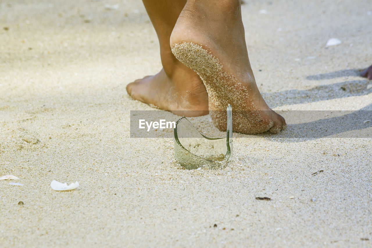 LOW SECTION OF PERSON STANDING ON SANDY BEACH