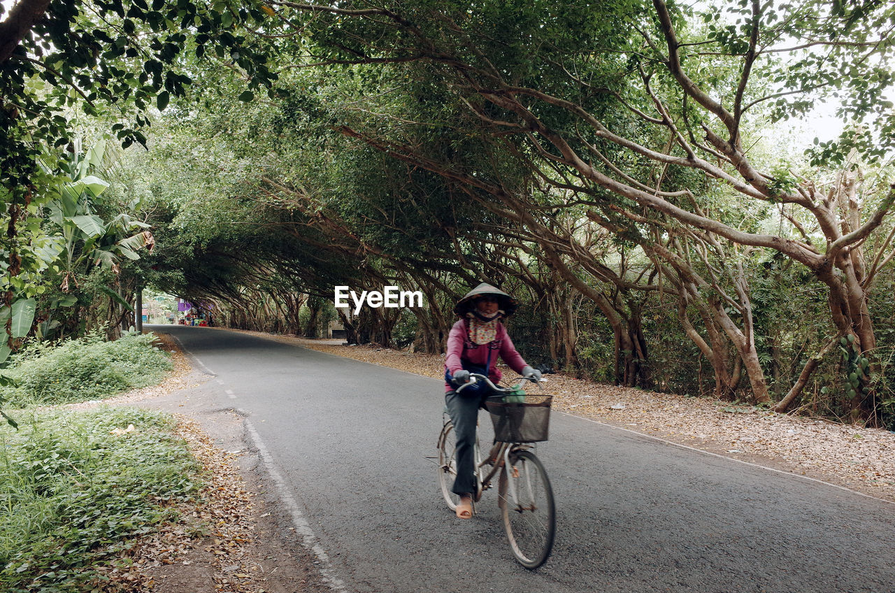 FULL LENGTH OF MAN RIDING BICYCLE ON ROAD