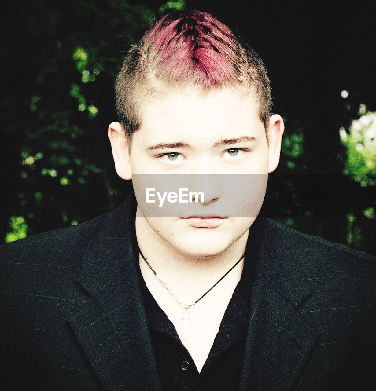 Portrait of teenage boy with dyed hair standing at park