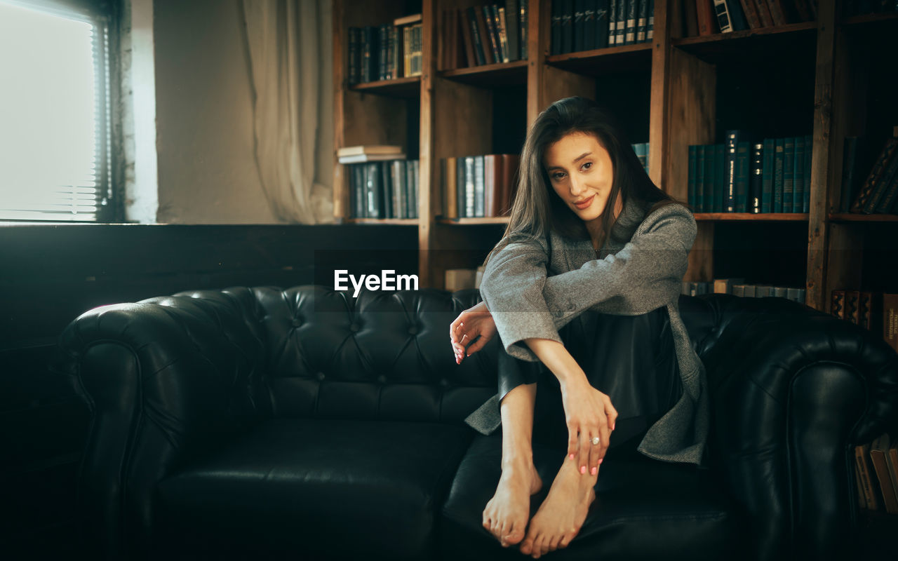 Young woman sitting on sofa at home