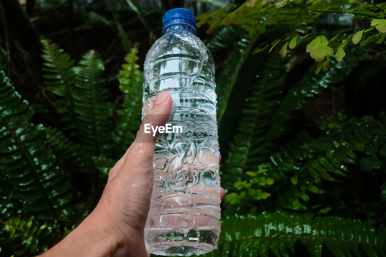 LOW SECTION OF PERSON HOLDING GLASS BOTTLE