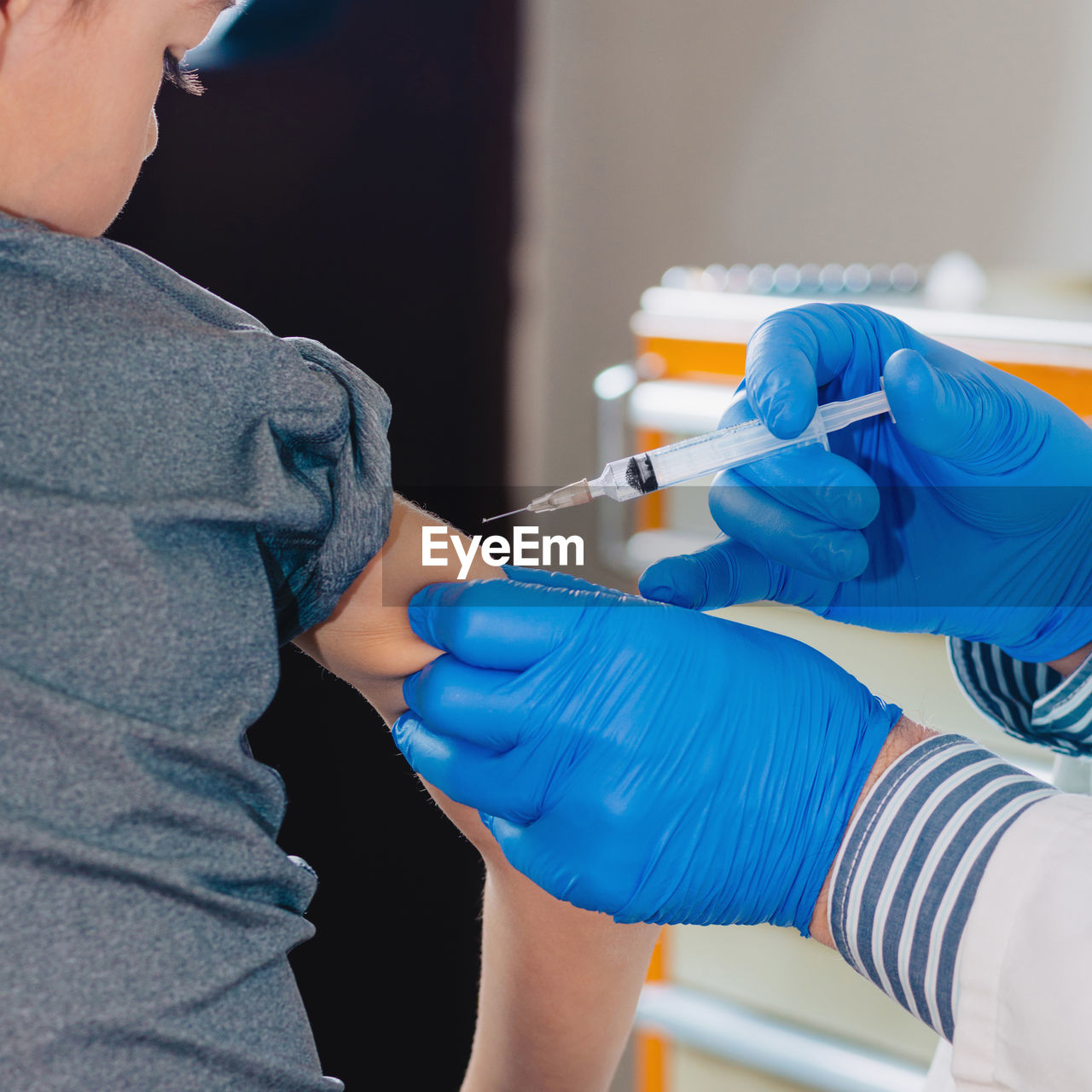 Cropped hands of doctor injecting syringe to boy in hospital