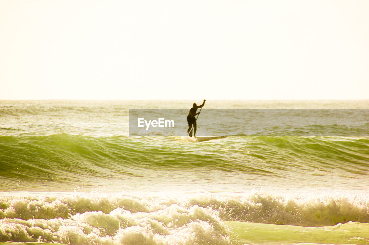 MAN JUMPING ON BEACH AGAINST SKY