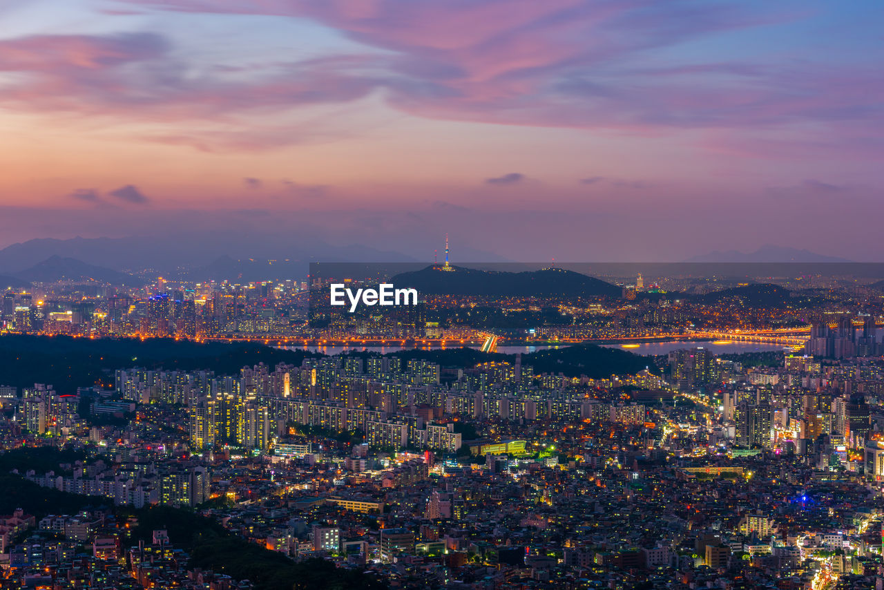 Illuminated cityscape against sky during sunset