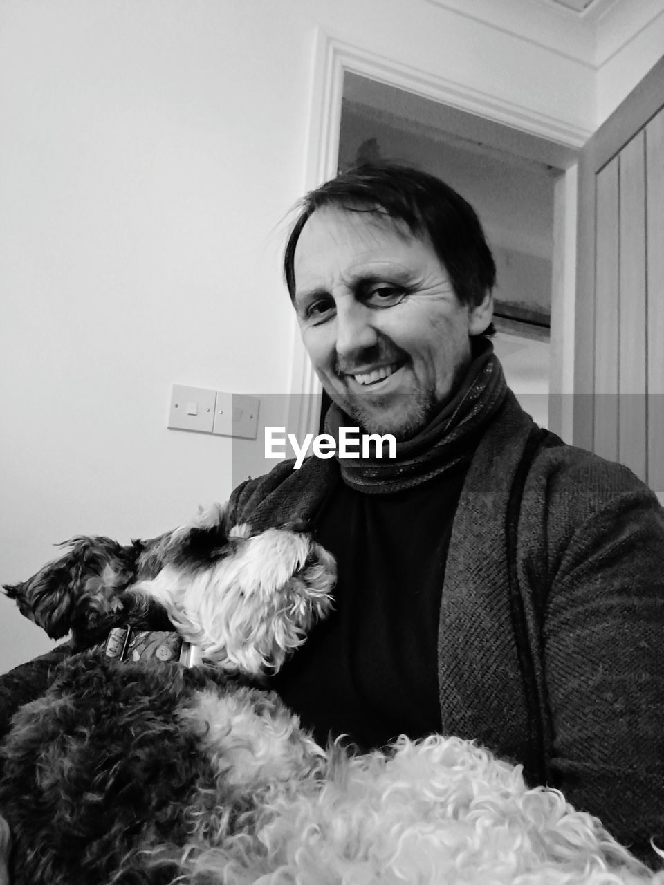 Portrait of smiling man with dog standing at home