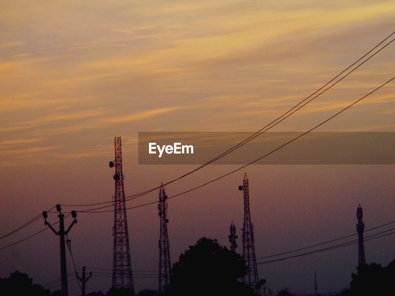 Low angle view of power lines against sky during sunset