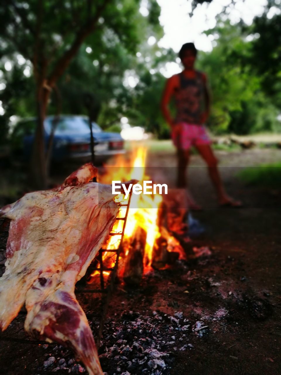 CLOSE-UP OF MAN ON BARBECUE GRILL AGAINST SKY