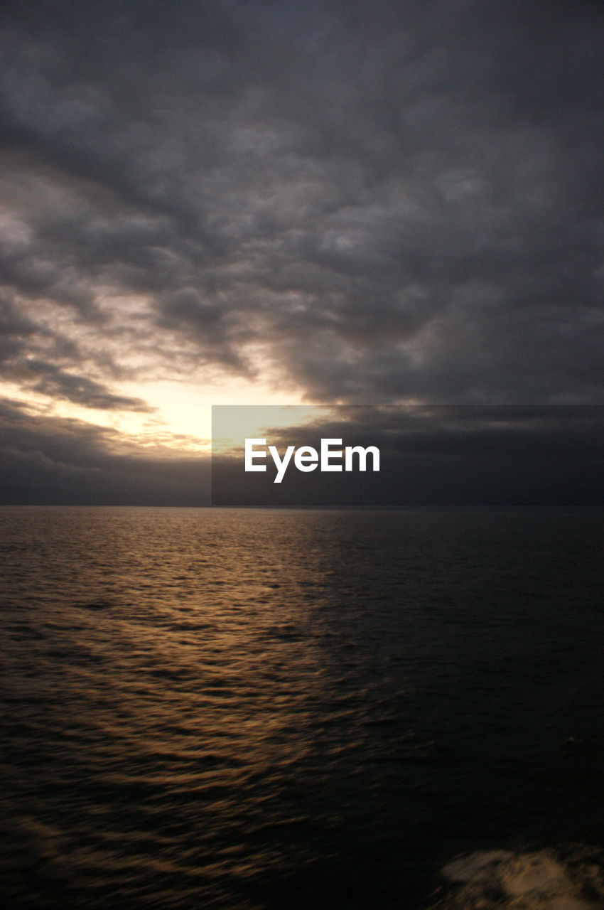 SCENIC VIEW OF SEA AGAINST CLOUDY SKY DURING SUNSET