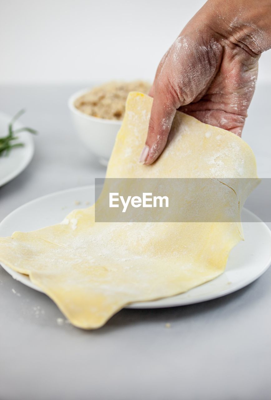 Cropped hand of woman holding dough in plate