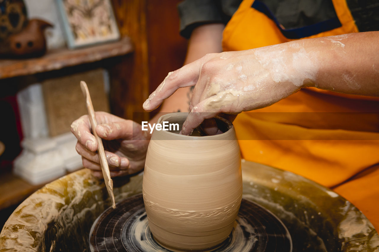 Crafts person working with clay on pottery wheel