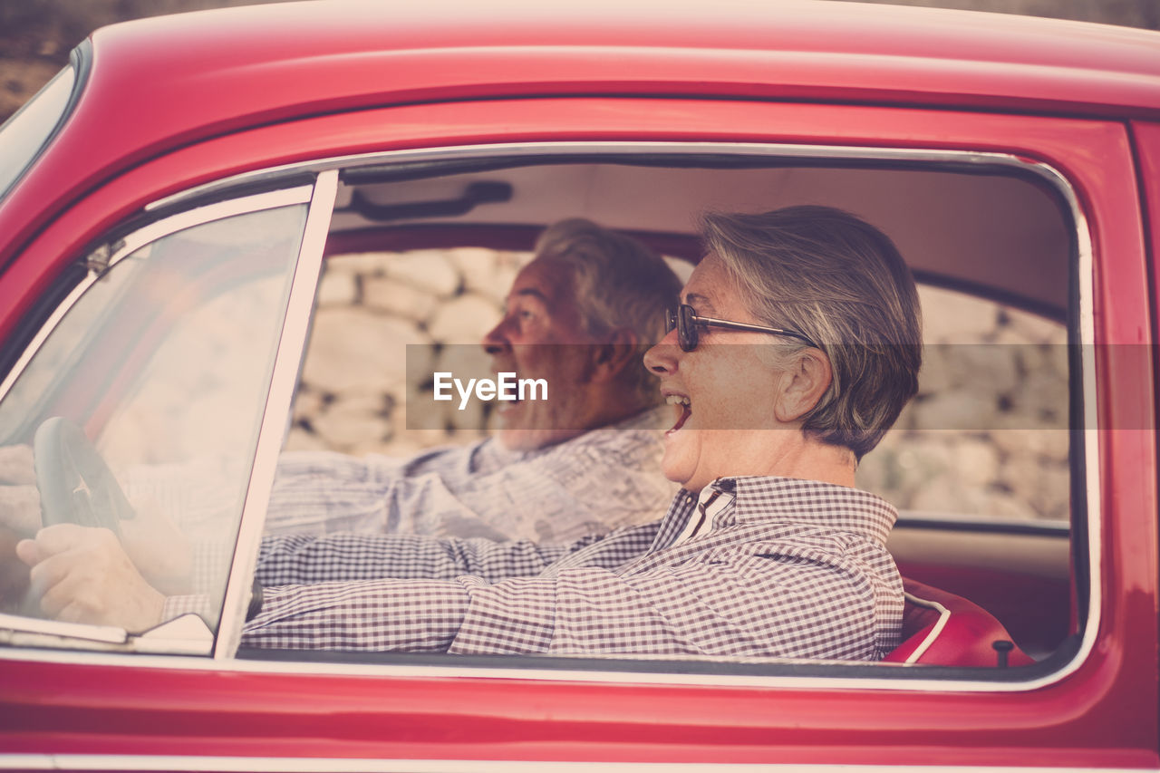 Cheerful senior couple traveling in car