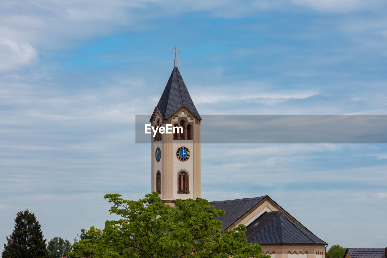 LOW ANGLE VIEW OF CLOCK TOWER AMIDST TREES AND BUILDING AGAINST SKY