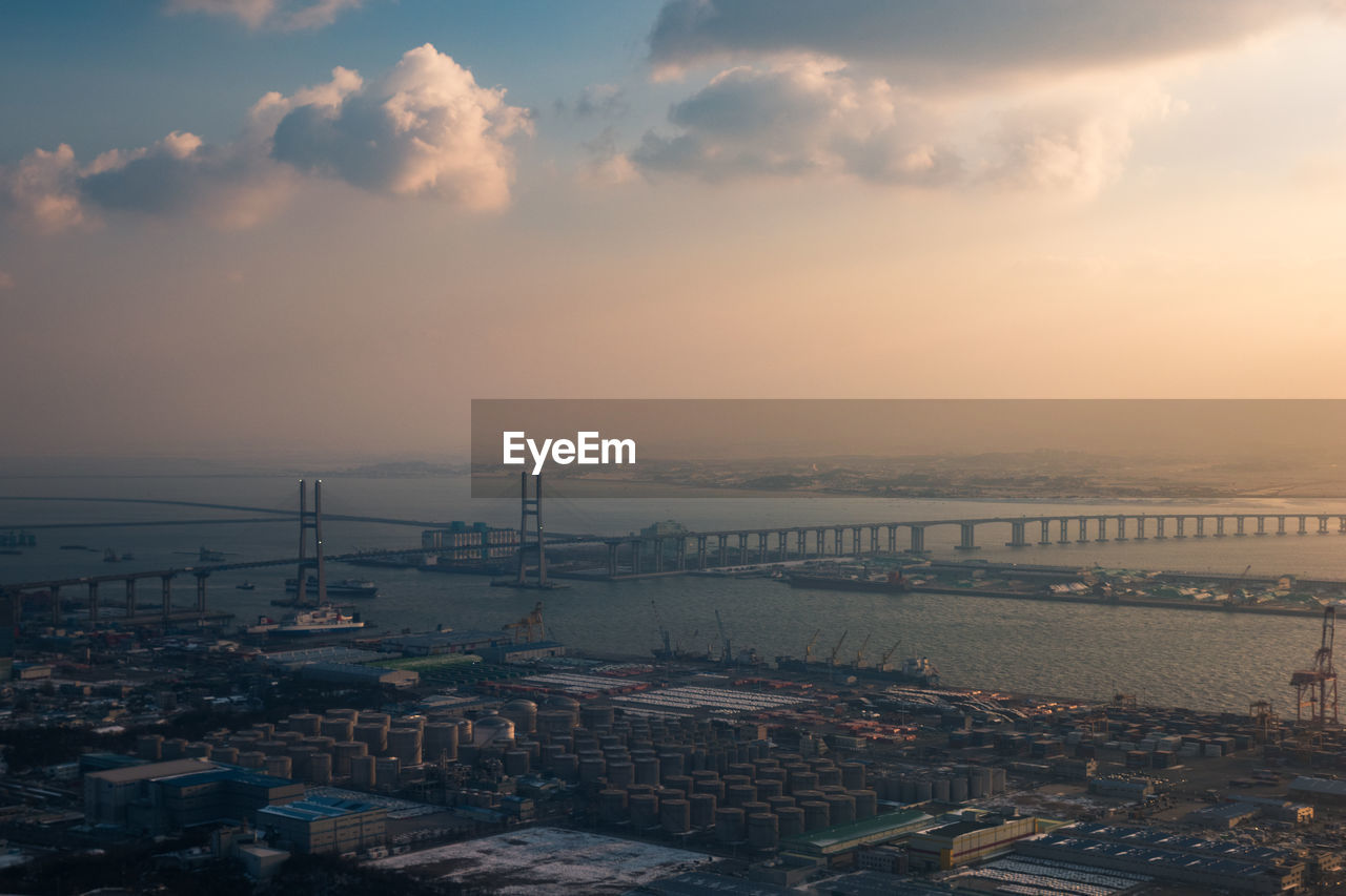 High angle view of commercial dock at harbor against sky during sunset