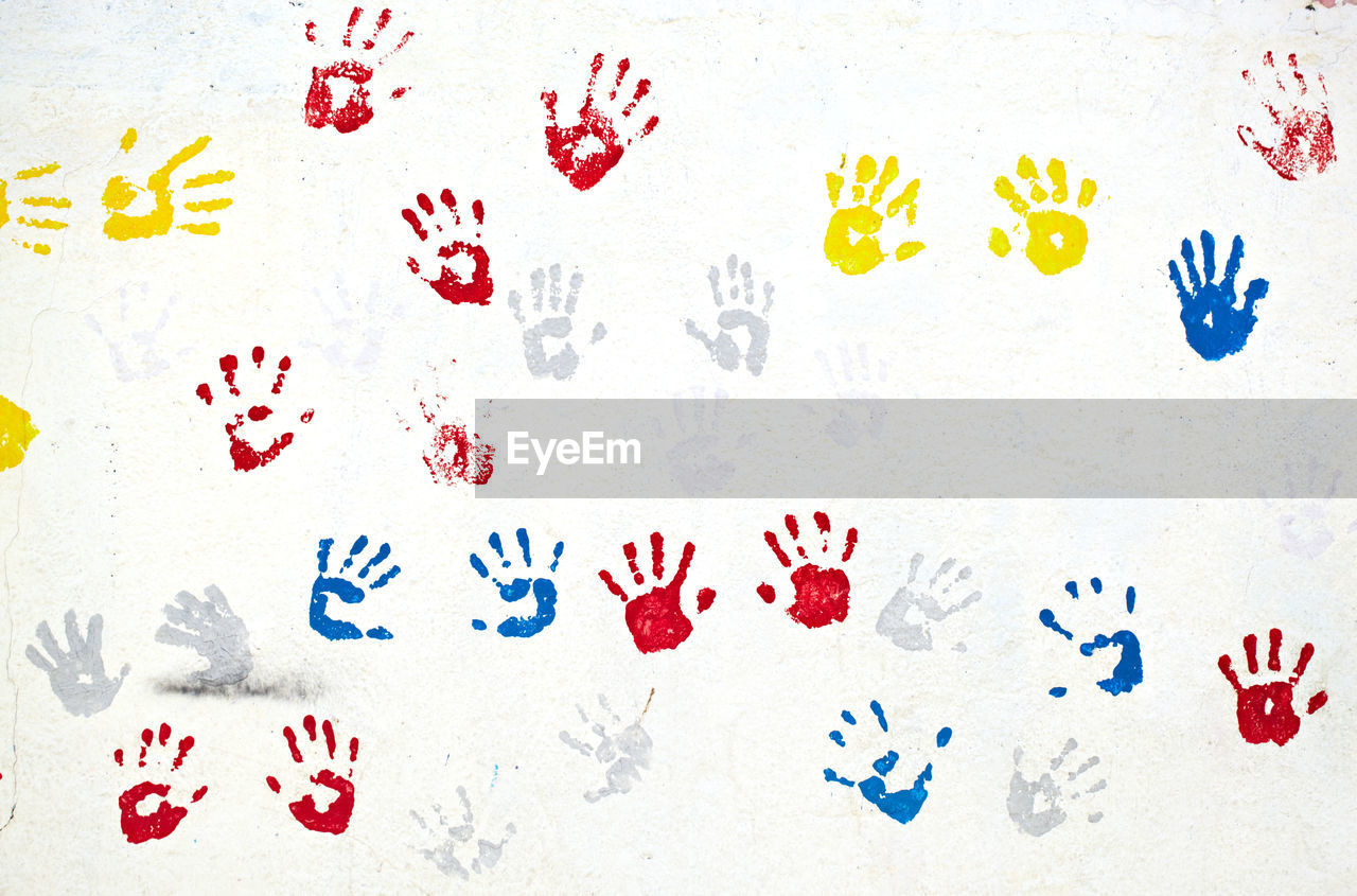 Close-up of colorful handprints on white wall