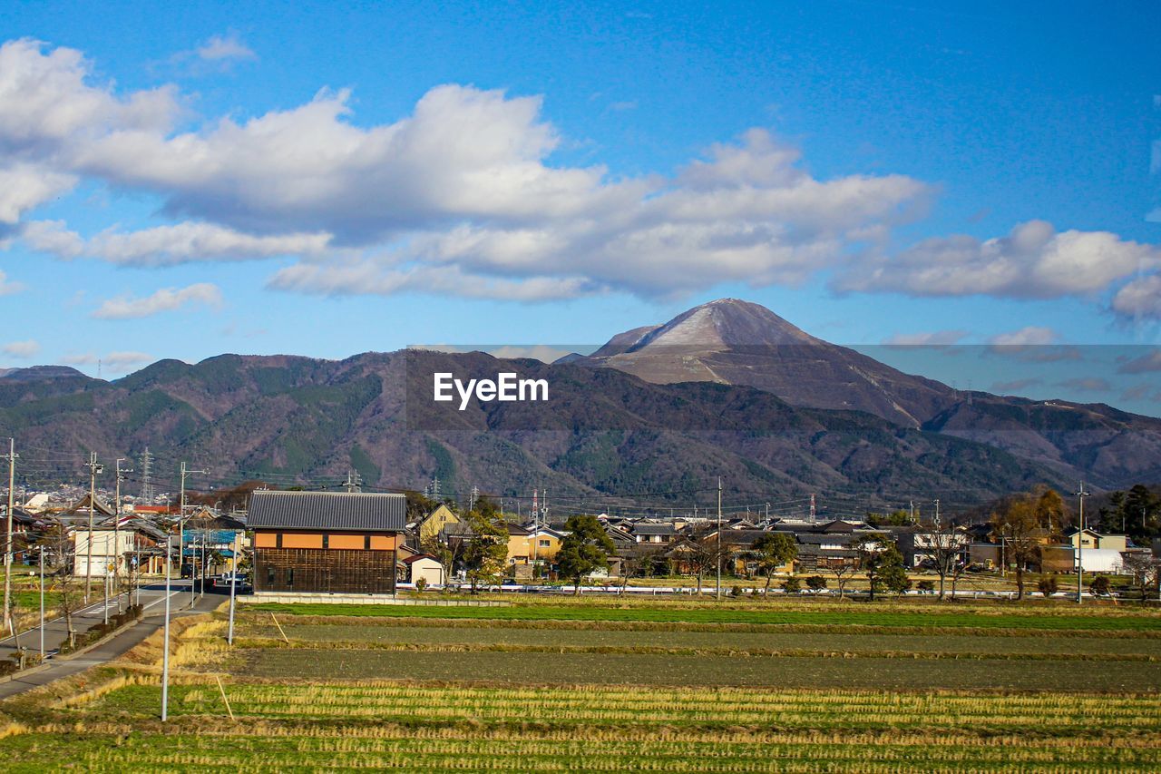 SCENIC VIEW OF FIELD AND HOUSES AGAINST SKY