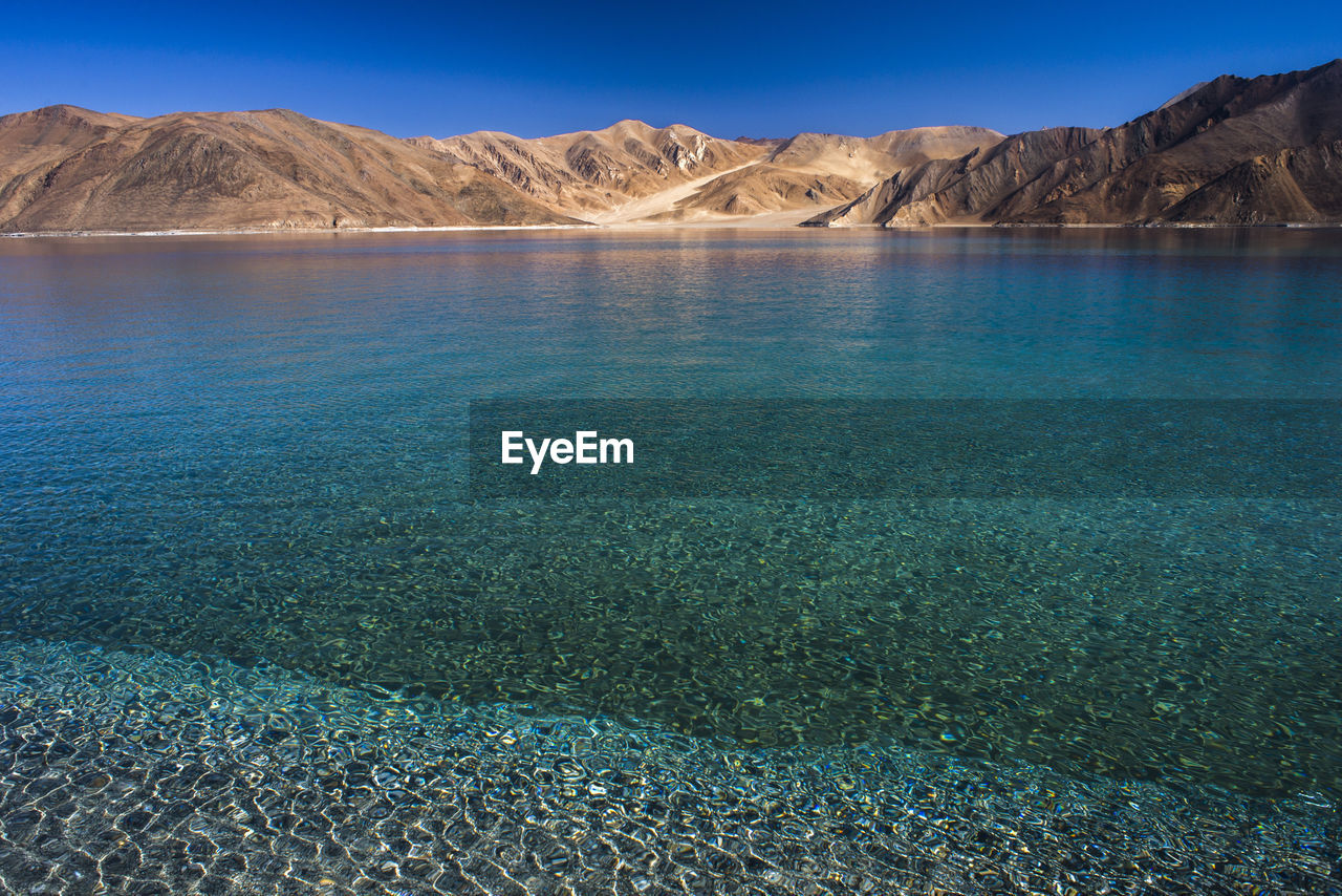 Scenic view of lake and mountains against blue sky