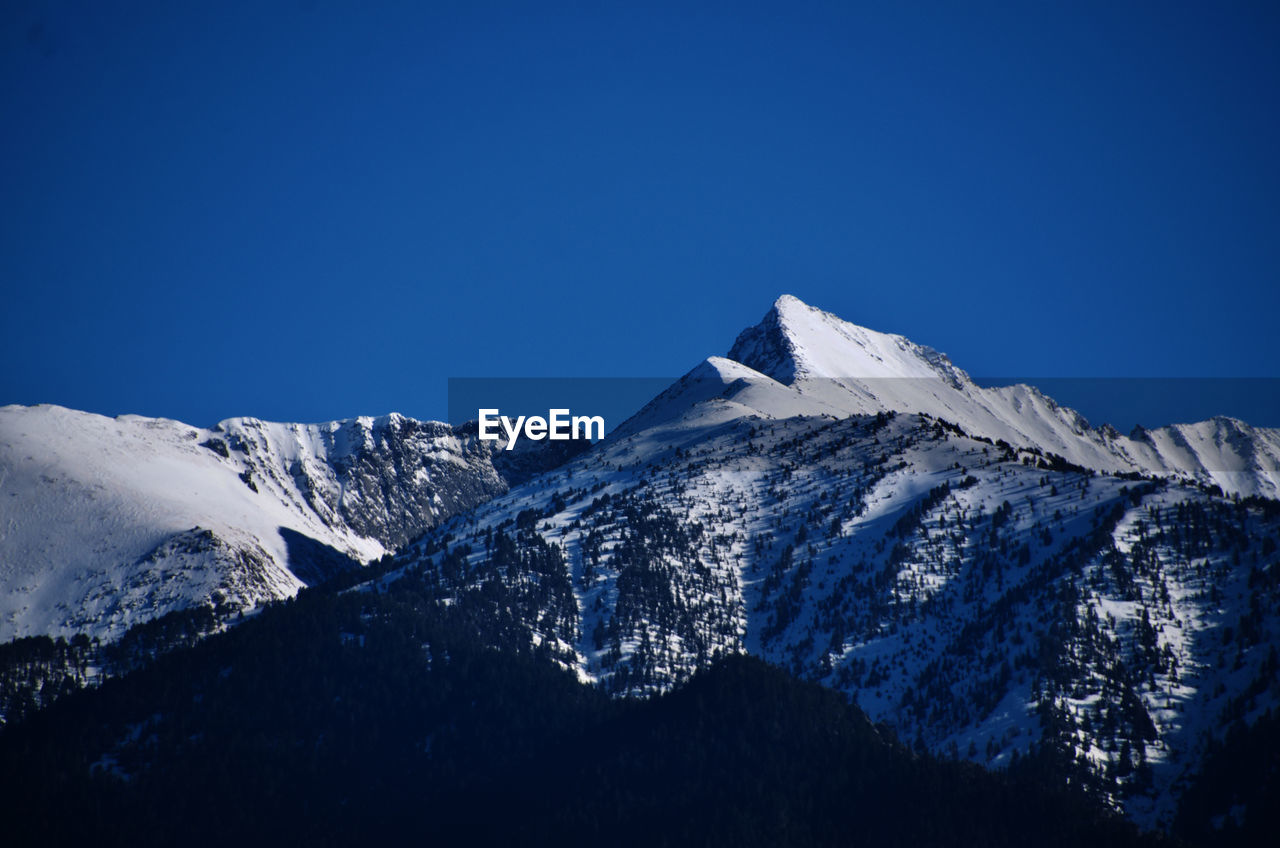 Scenic view of snowcapped mountains against clear blue sky