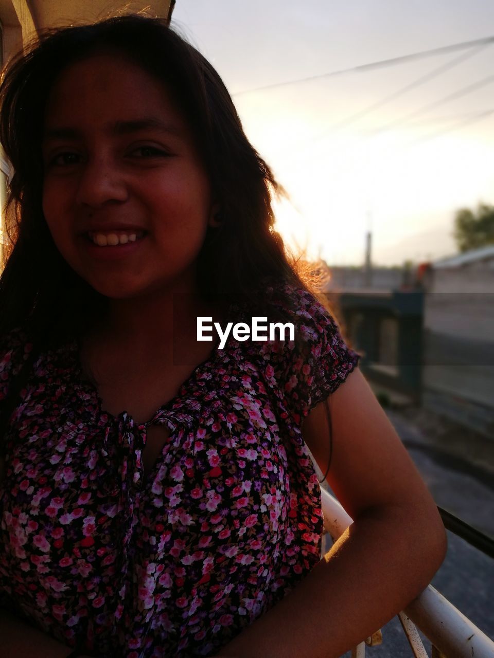 PORTRAIT OF SMILING YOUNG WOMAN AGAINST SKY