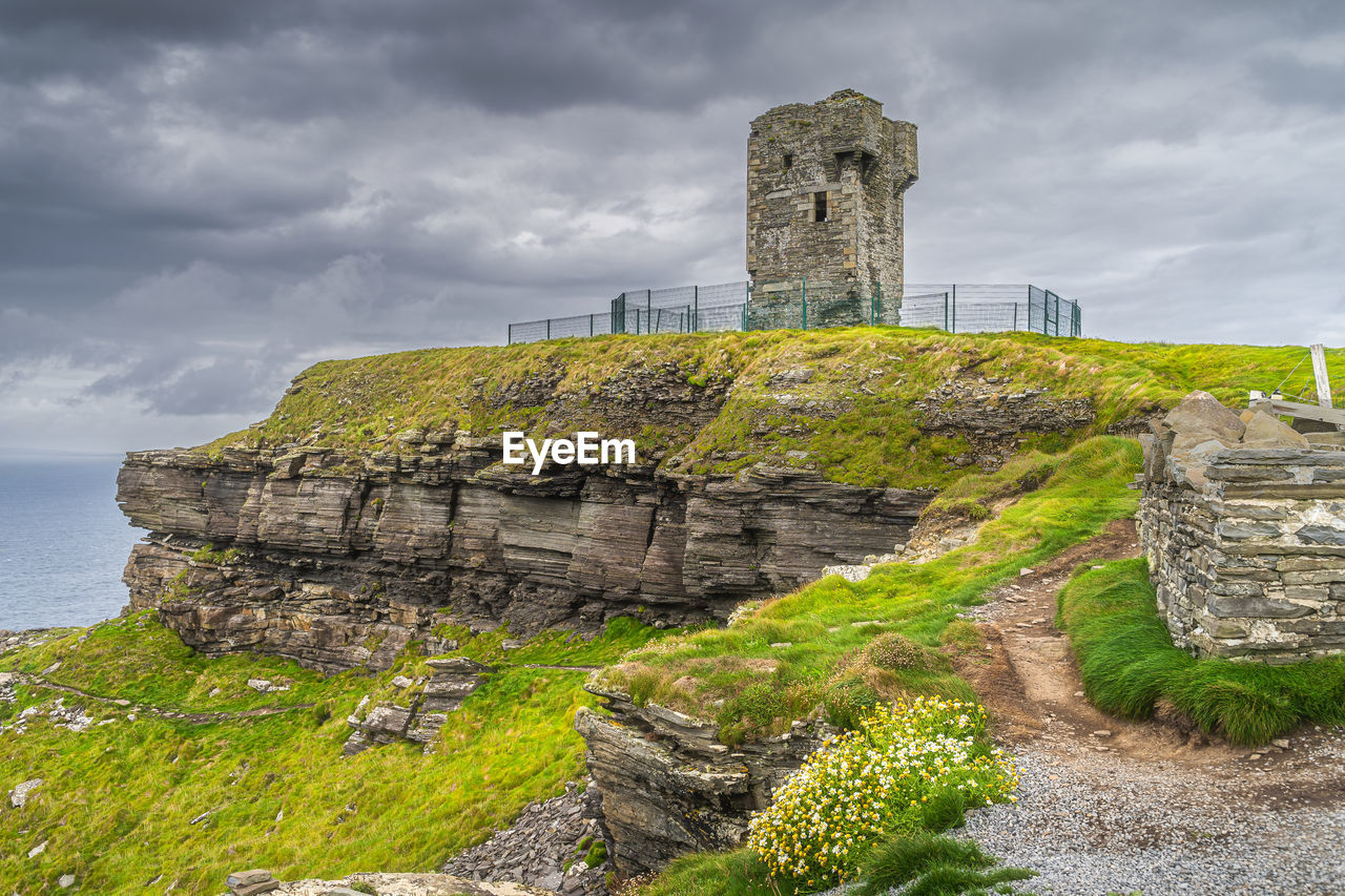 ruins, history, architecture, the past, cloud, sky, built structure, fortification, rock, travel destinations, landmark, archaeological site, old ruin, travel, nature, castle, coast, ancient, building exterior, cliff, land, water, building, sea, tourism, overcast, ancient history, no people, environment, tower, wall, old, stone material, terrain, landscape, plant, hill, outdoors, storm, scenics - nature, fort, ruined, beach, medieval, ancient civilization, beauty in nature, storm cloud, protection, grass, archaeology, security, stone wall