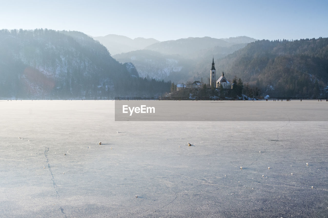 Scenic view of frozen lake bled by mountain against sky