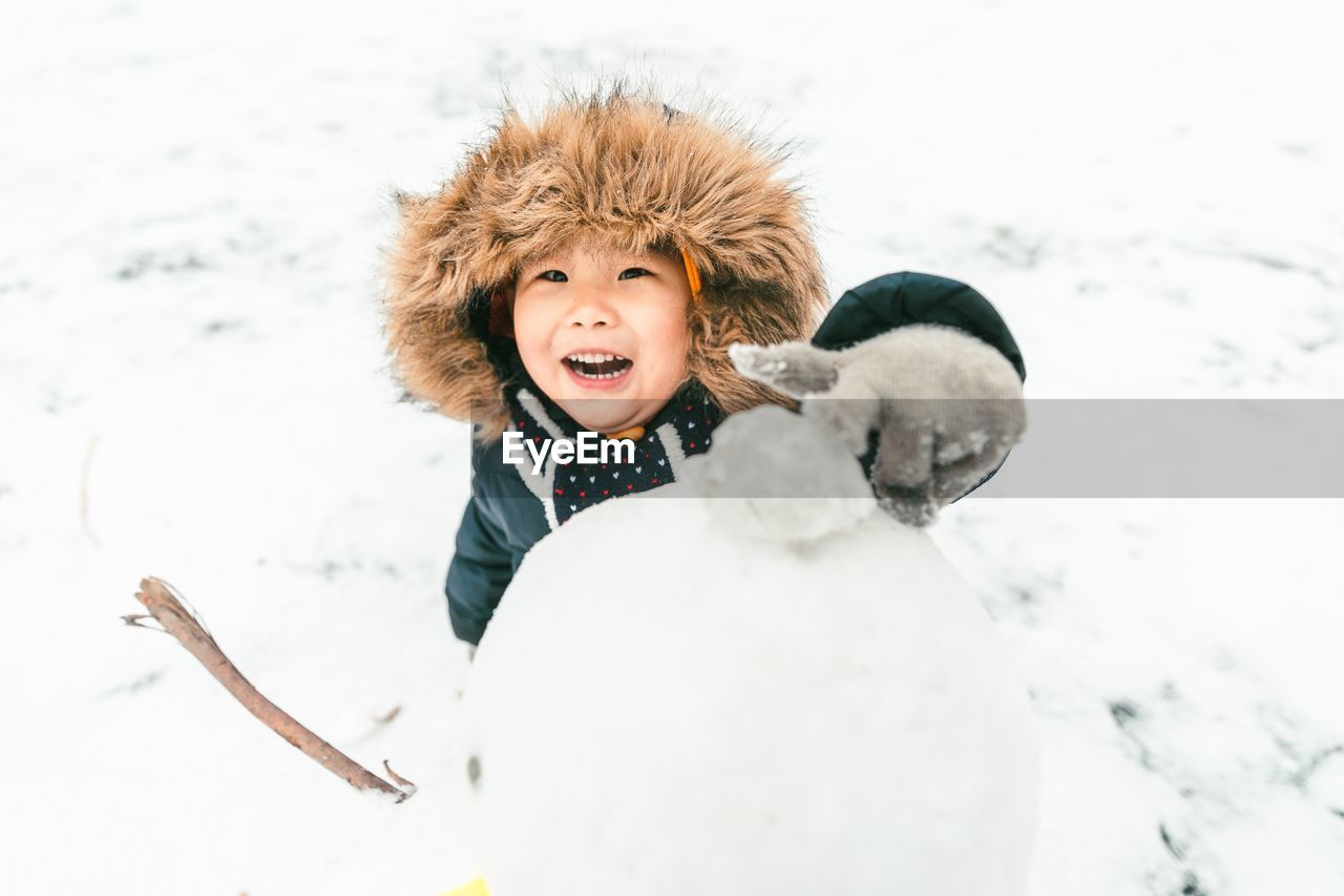 portrait of woman with dog on snow covered field