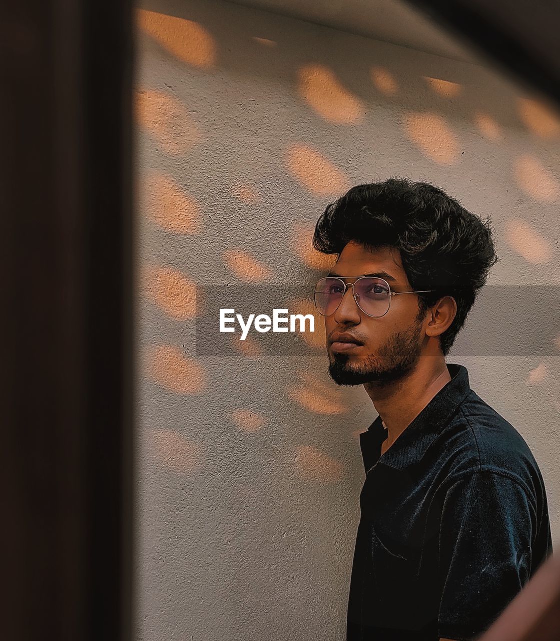 Portrait of young man standing against wall