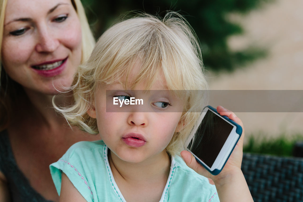 Close-up of cute girl holding mobile phone at home