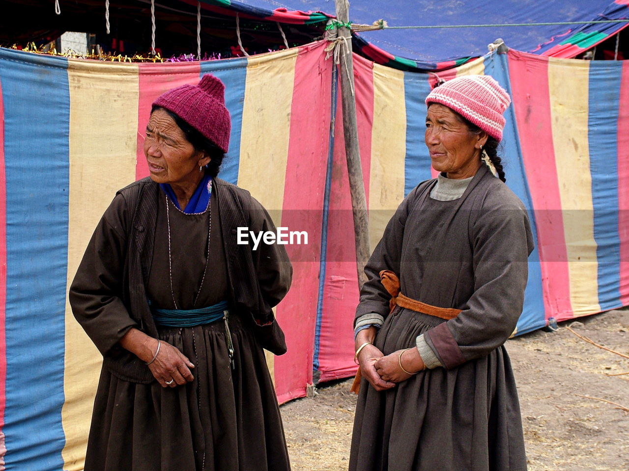 Mature women wearing traditional clothing standing by tent