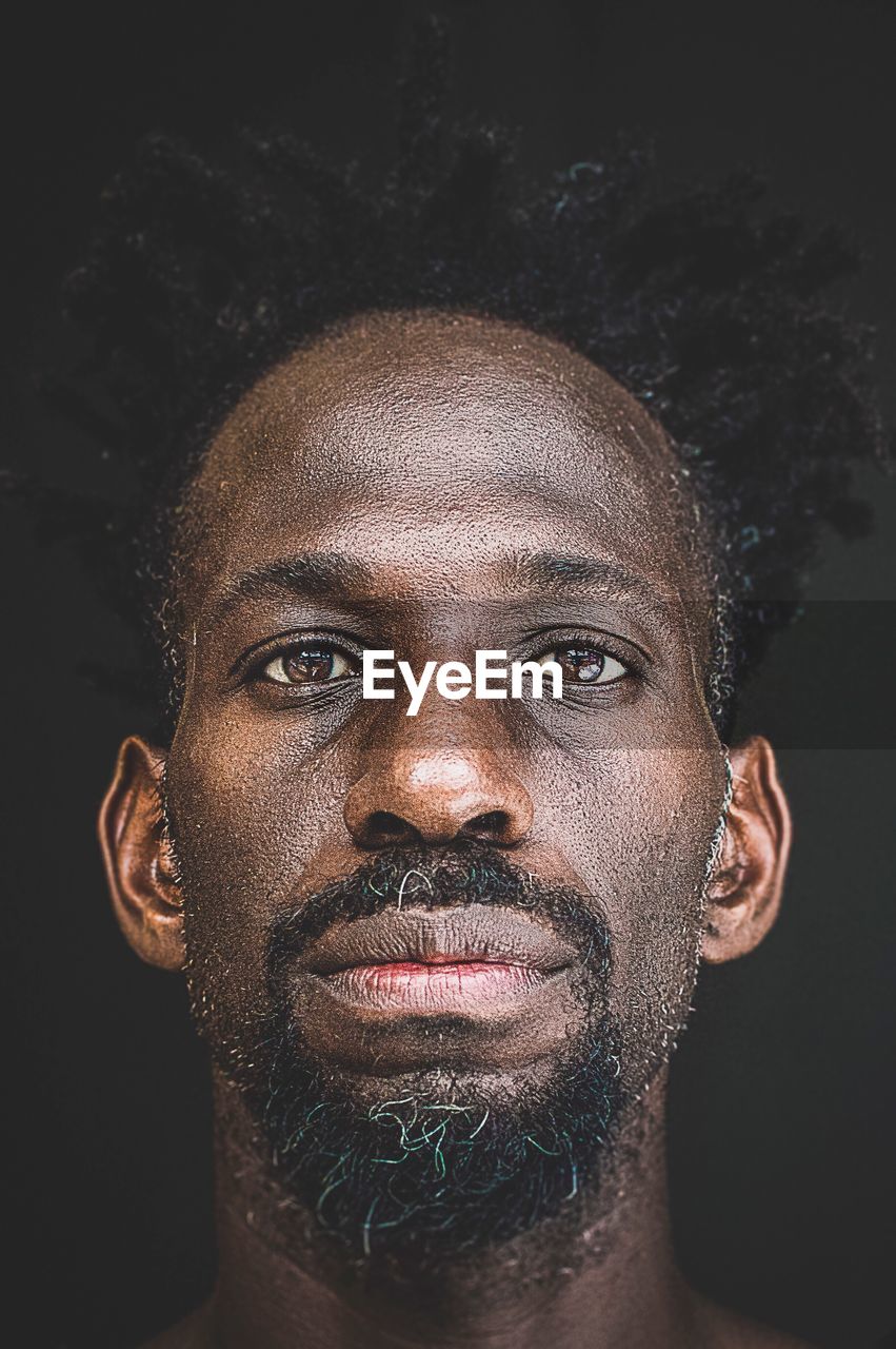 Close-up portrait of man against black background