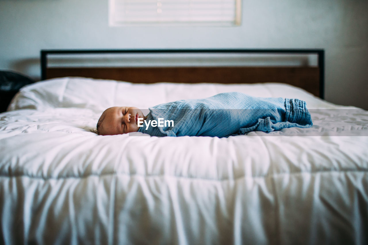 Center portrait of newborn sleeping on bed