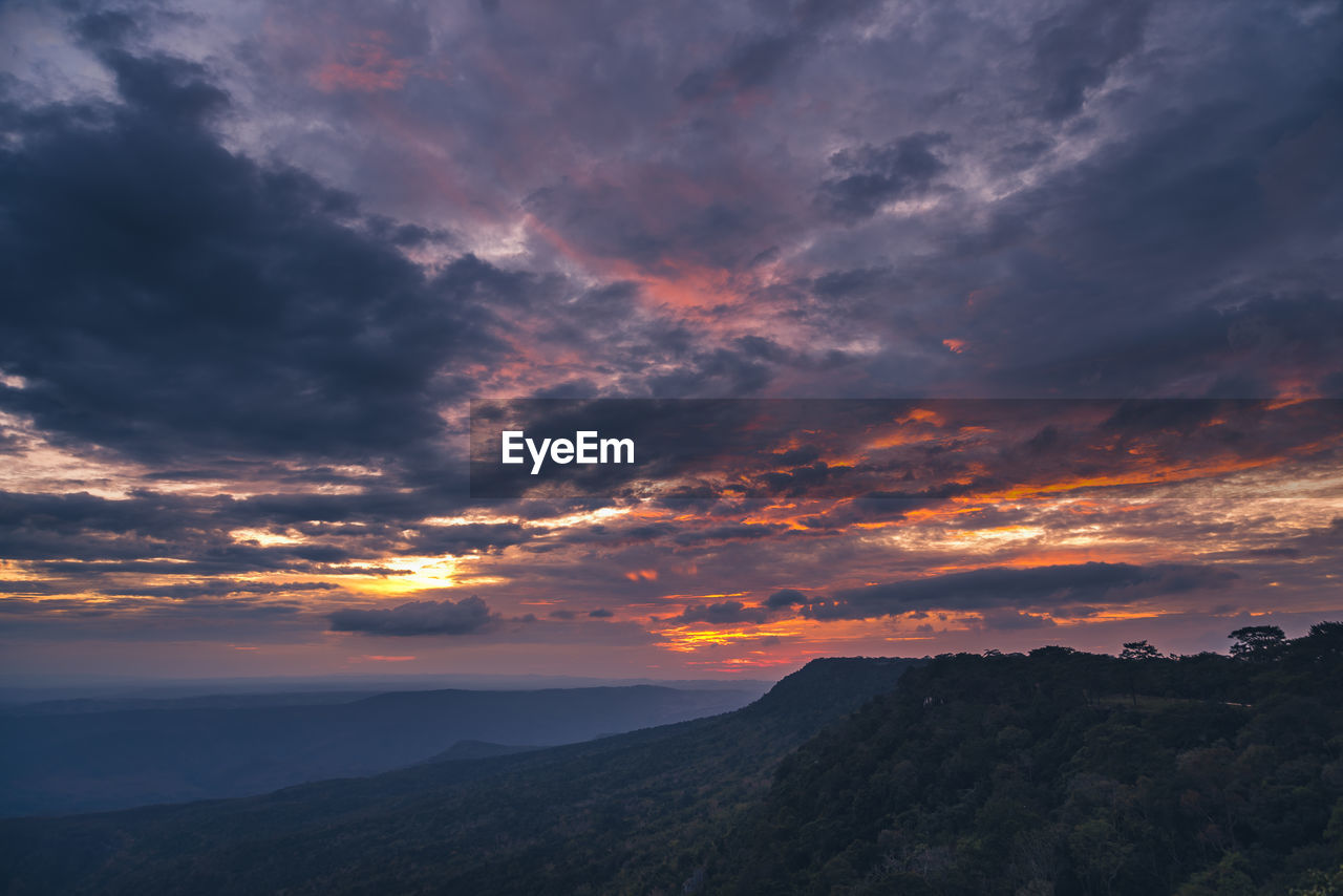 Scenic view of dramatic sky over silhouette mountains during sunset
