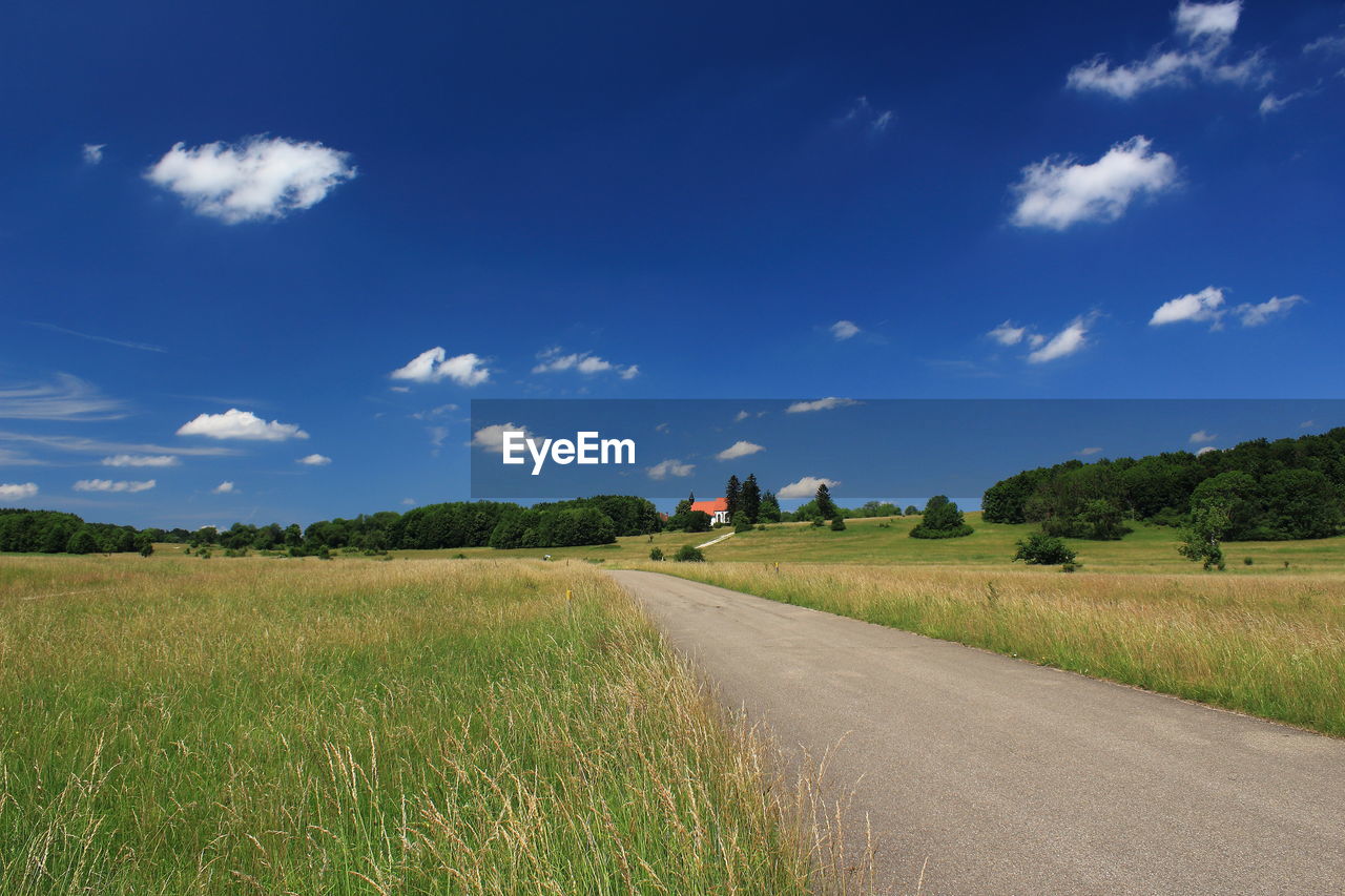 Road amidst field against sky