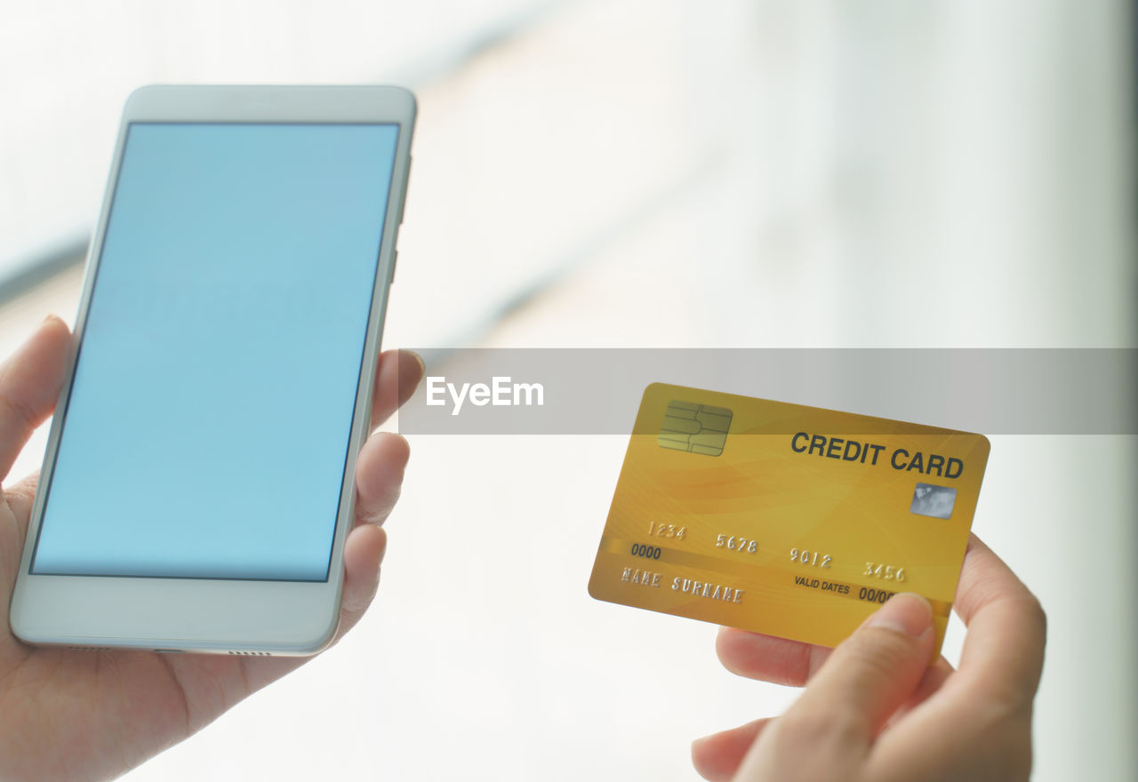 Woman holding mock up credit card while using smartphone for shopping online by credit card.