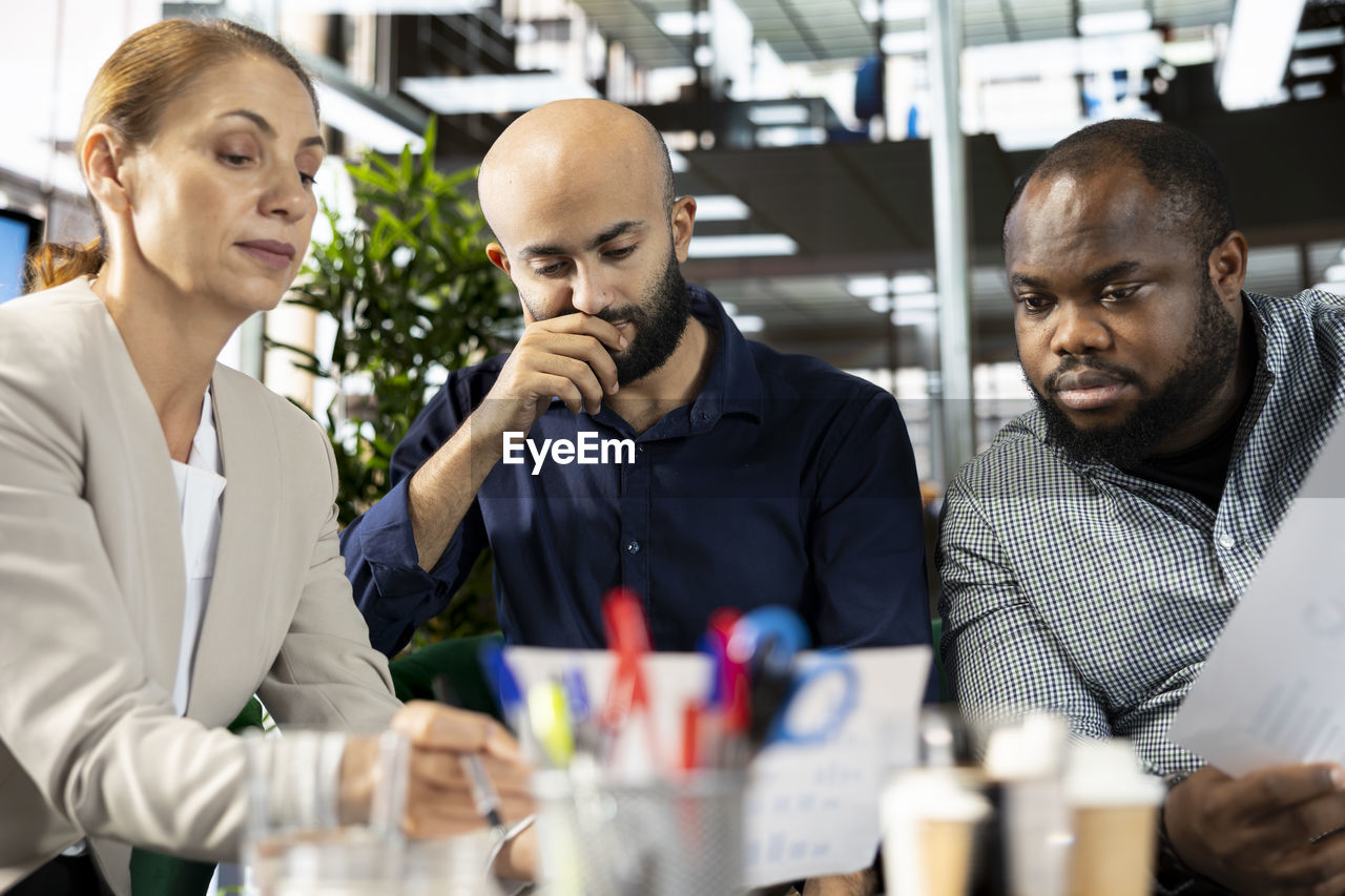 adult, men, group of people, business, indoors, communication, occupation, working, business finance and industry, mature adult, teamwork, cooperation, small group of people, women, person, talking, office, coworker, discussion, young adult, businessman, technology, sitting, selective focus, shaved head, table, meeting, looking, human face, clothing, female, food and drink