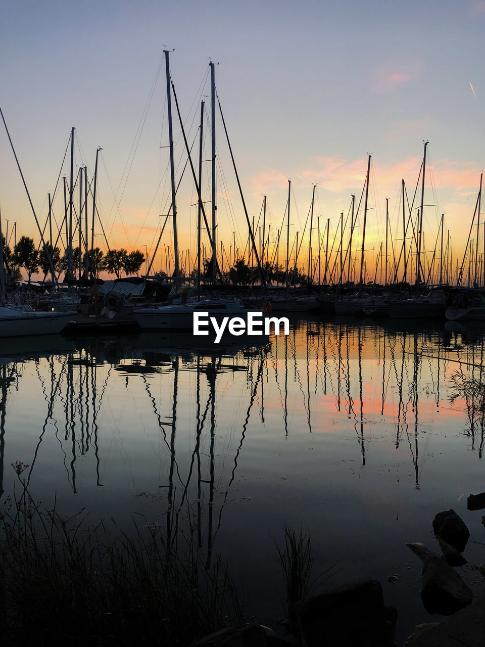 Sailboats in lake against sky during sunset